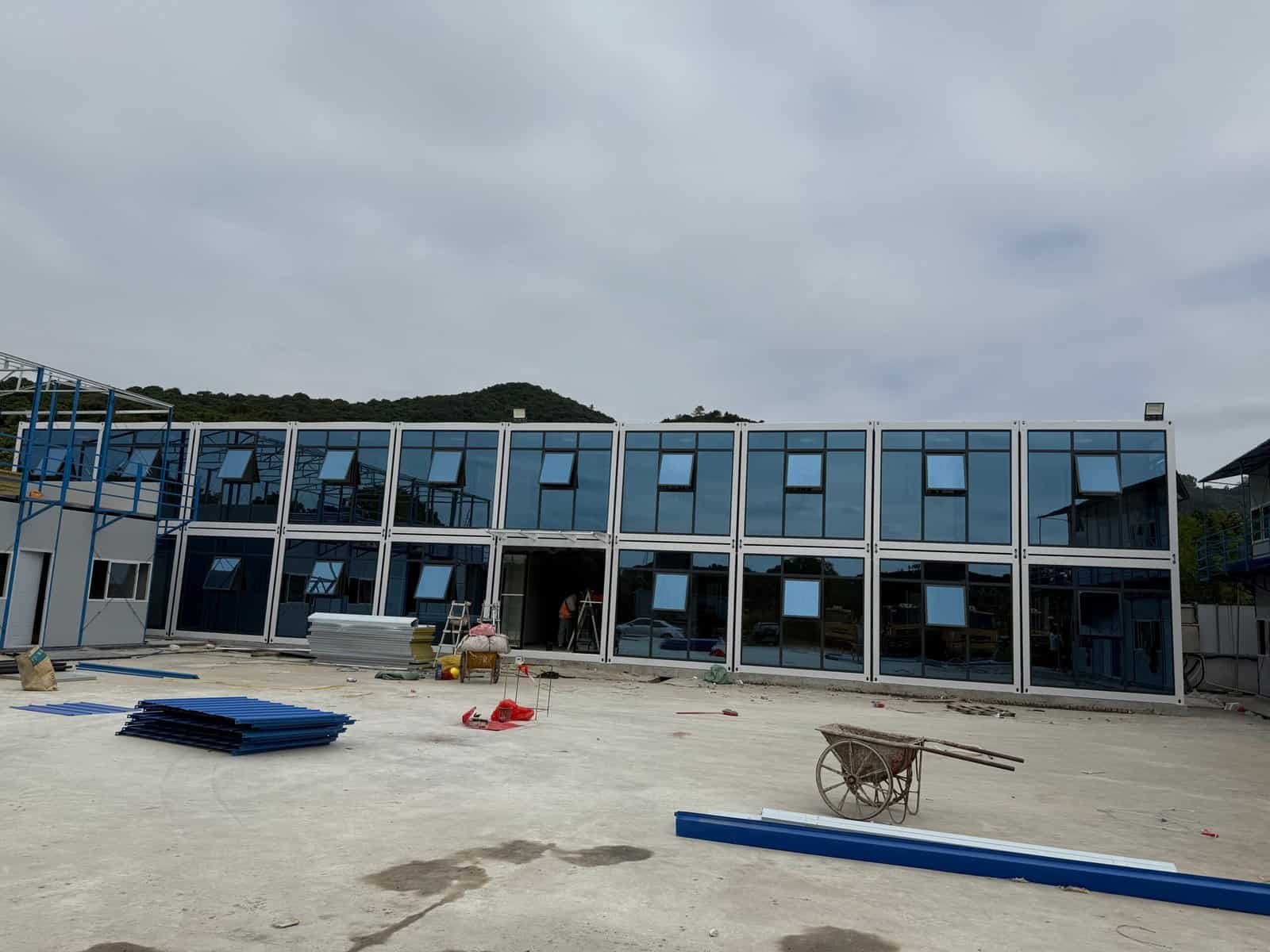 Portable modular building under construction with glass facade, ideal for commercial or office space, showcasing modern prefab architecture and quick assembly.