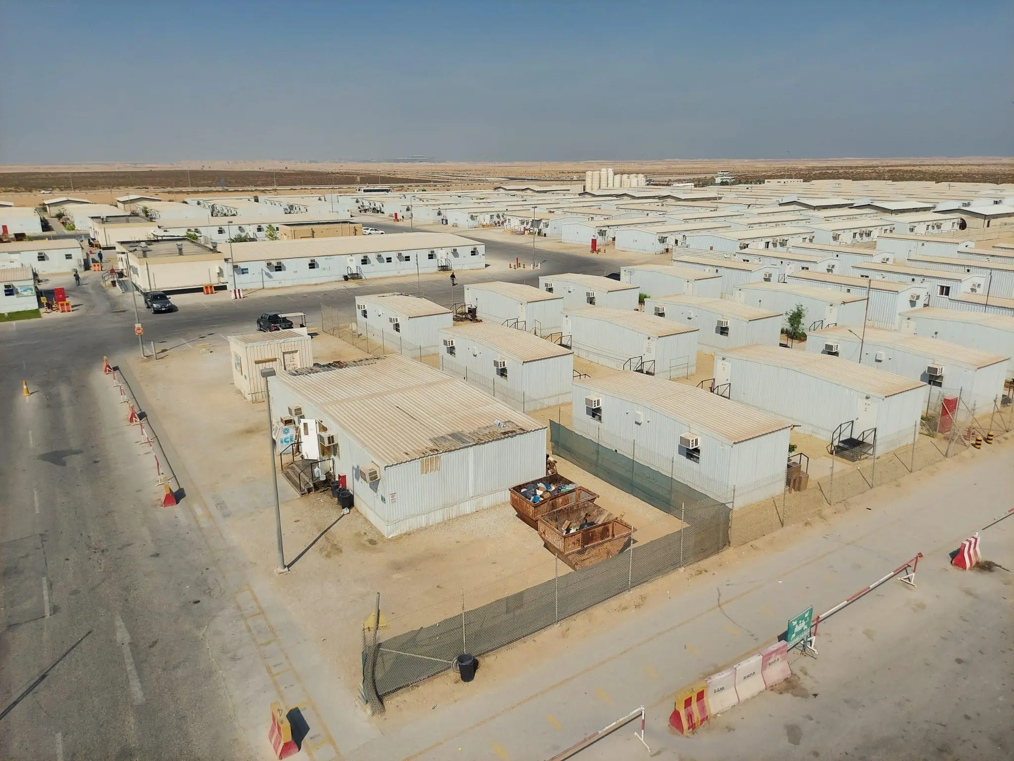 Aerial view of a modular camp with rows of accommodation buildings and internal roads