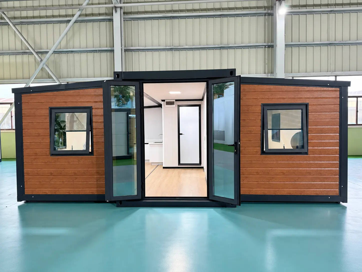 Front view of a 20ft expandable container house with wood-look cladding, double glass doors and two opening windows.