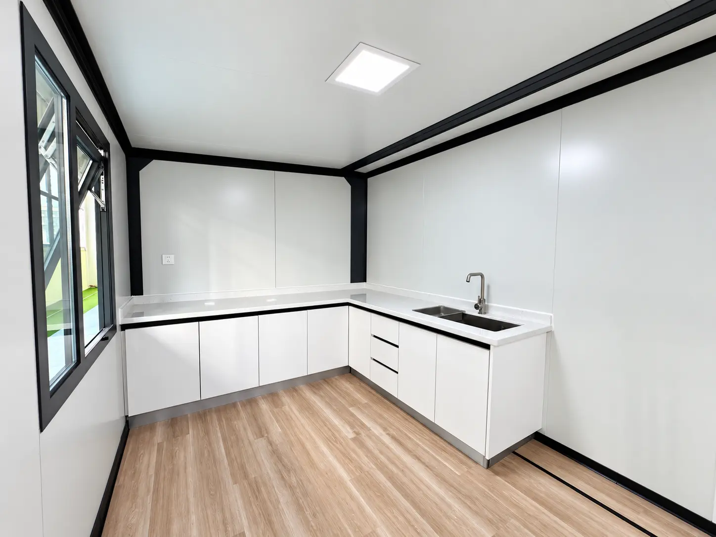 L-shaped kitchen fit-out with cabinetry, worktops and sink inside a modular building unit