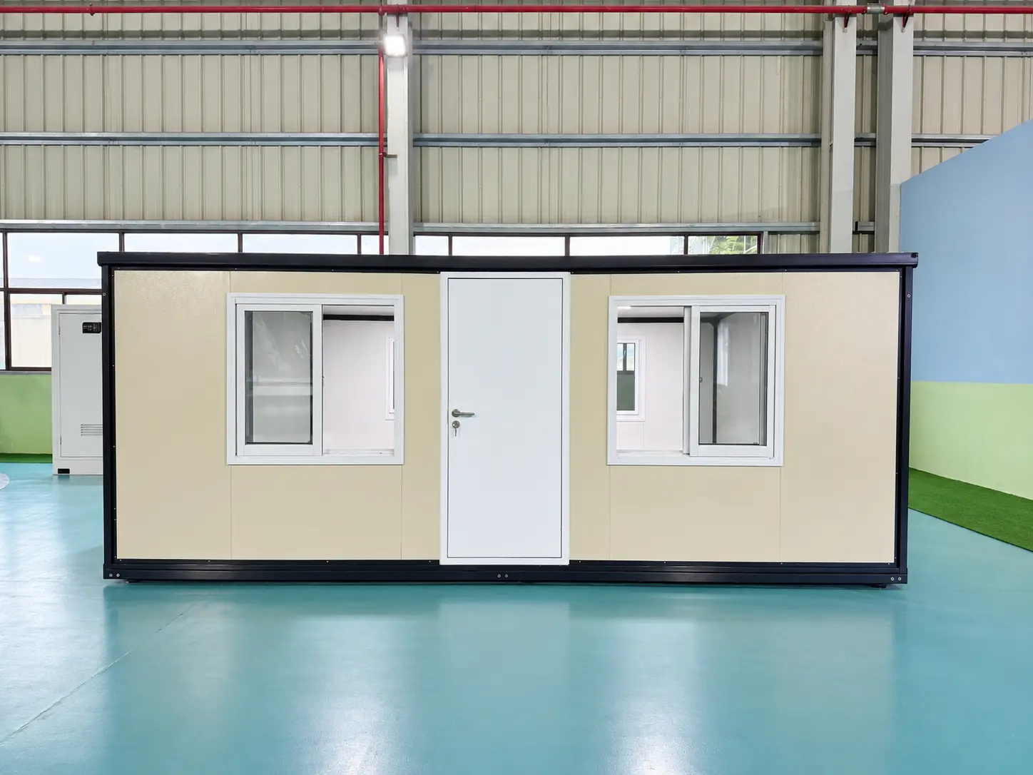 Front view of a 700 model double-wing expandable container house with a centered white door and two windows.
