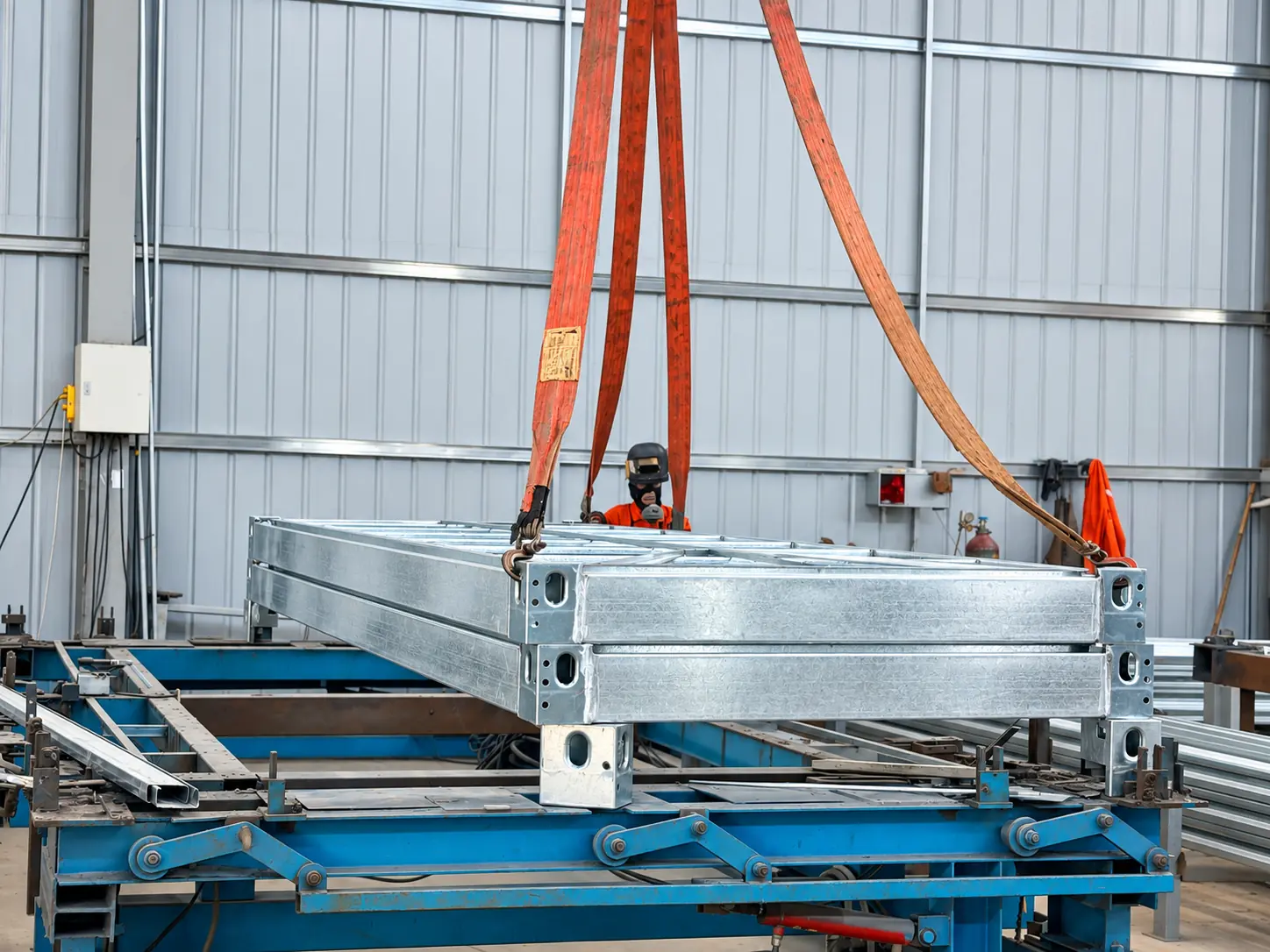 Galvanized modular frame components being lifted in the factory