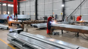Premium Modular House workers welding galvanized steel frames in a modular building factory.