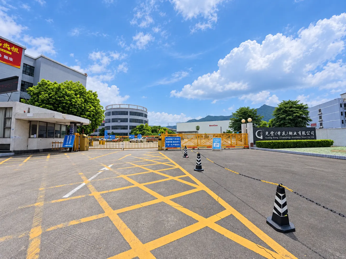 Industrial factory entrance with a yellow access gate, parking markings and mountain backdrop