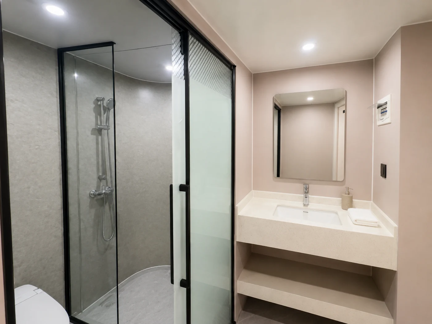 Capsule bathroom fit-out example with an enclosed shower, vanity and mirror