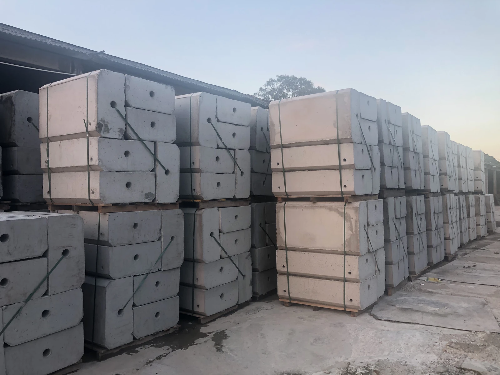 Precast concrete hoarding foundation blocks stacked in storage.