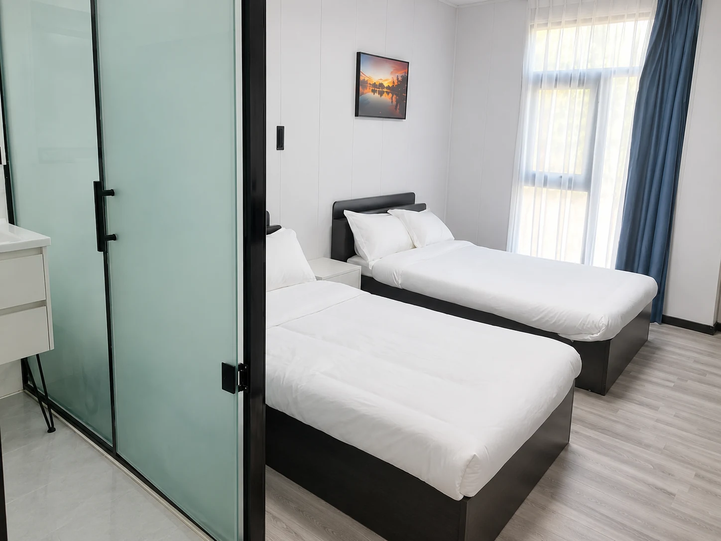 Referencyjna aranżacja pokoju Premium Modular House z dwoma pojedynczymi łóżkami i wydzieloną łazienką